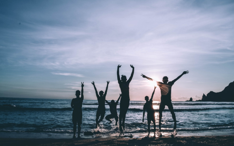Joyful family celebrating Financial Freedom and success on a sunlit beach, leaping into the air with elation, symbolizing their triumph in affiliate marketing and a bright, secure financial future.